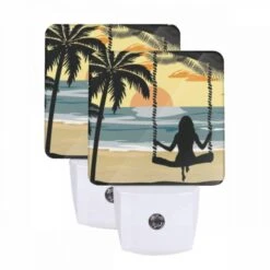 Night Light Set Of 2, A Woman Is Sitting On A Swing In Front Of The Ocean.